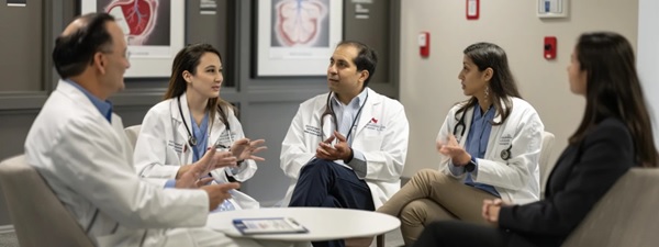 The image is a group of healthcare professionals sitting in a meeting.