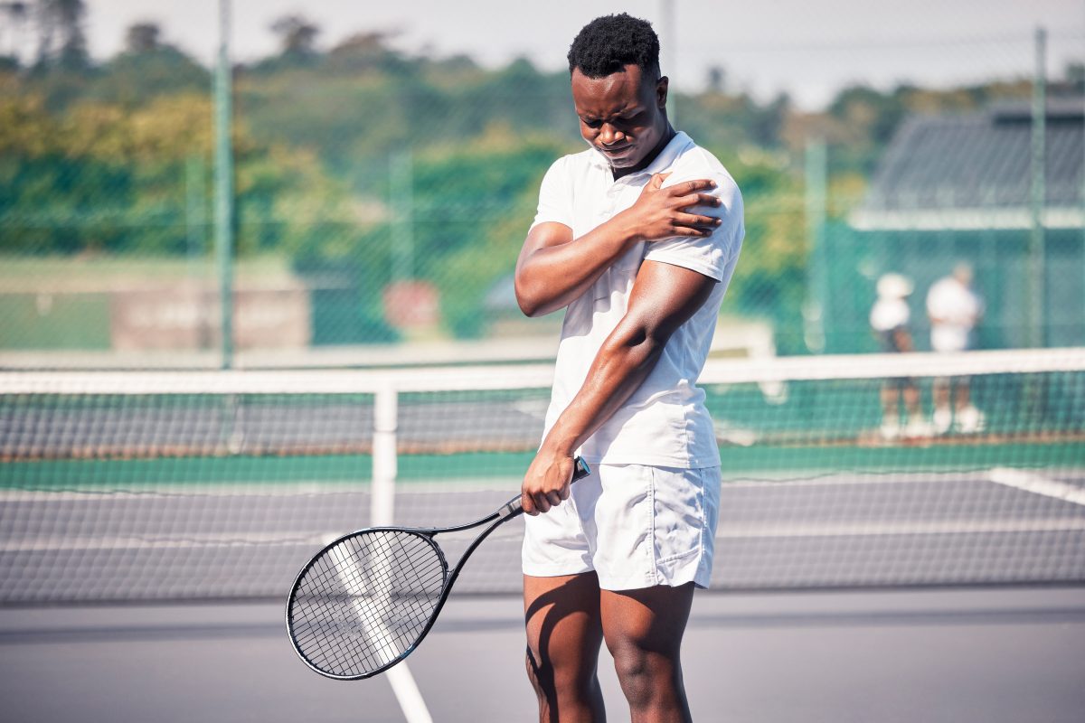 Sports, tennis and arm pain on court after training, game or match outdoors. Healthcare, tennis player and injured black man or athlete with muscle pain or inflammation after exercise or workout